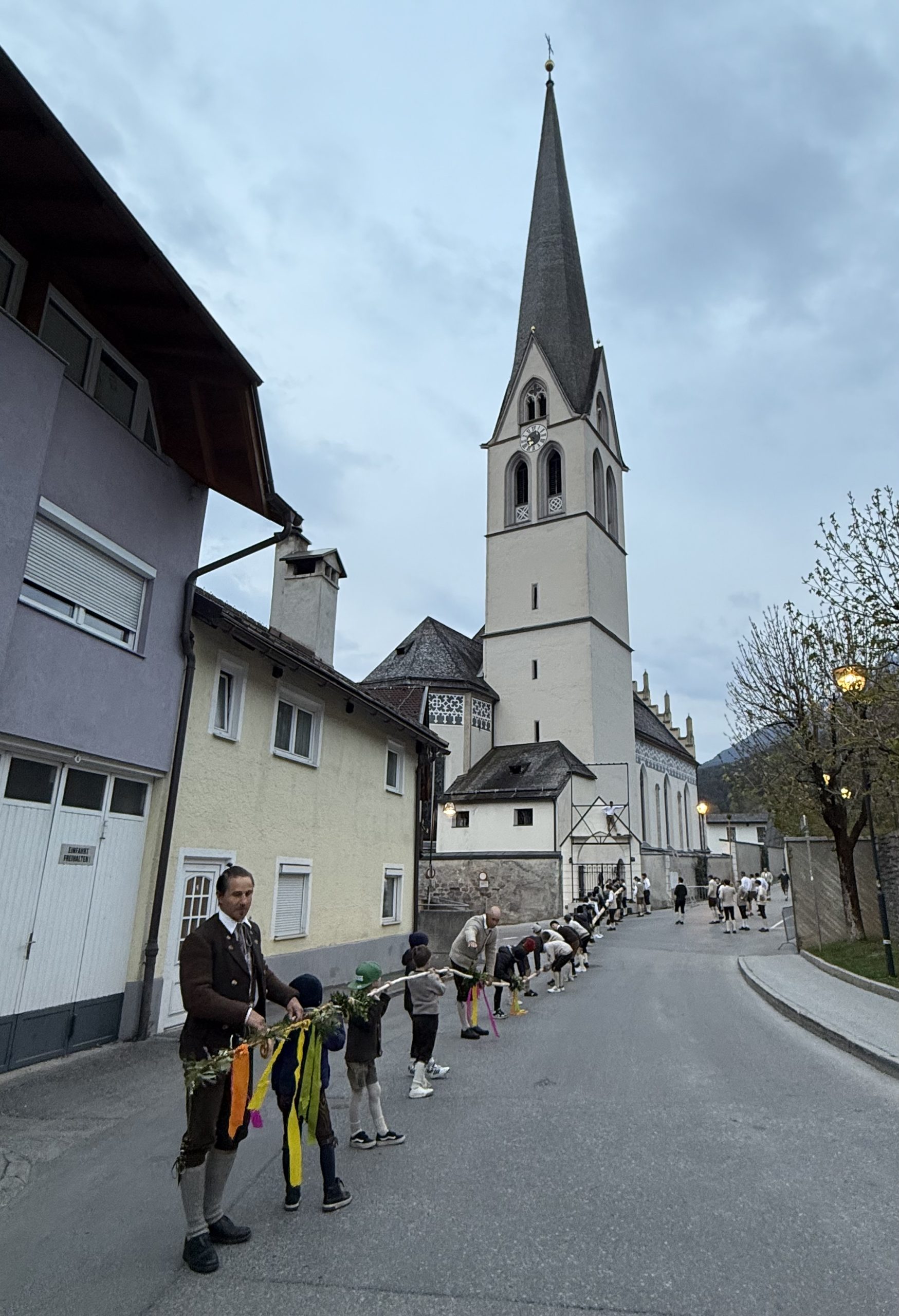 Die langen Holzlatten werden von zahlreichen Helfern in Position gelegt. Sie stehen vor der Kirche mit der mehr als 30 Meter langen Palmlatte