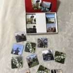 Ein Memory Spiel mit Bildern aus Destinationen weltweit. Die Schachtel ist rot und man sieht viele kleinere Karten davor auf einer hellen Oberfläche verteilt liegen.