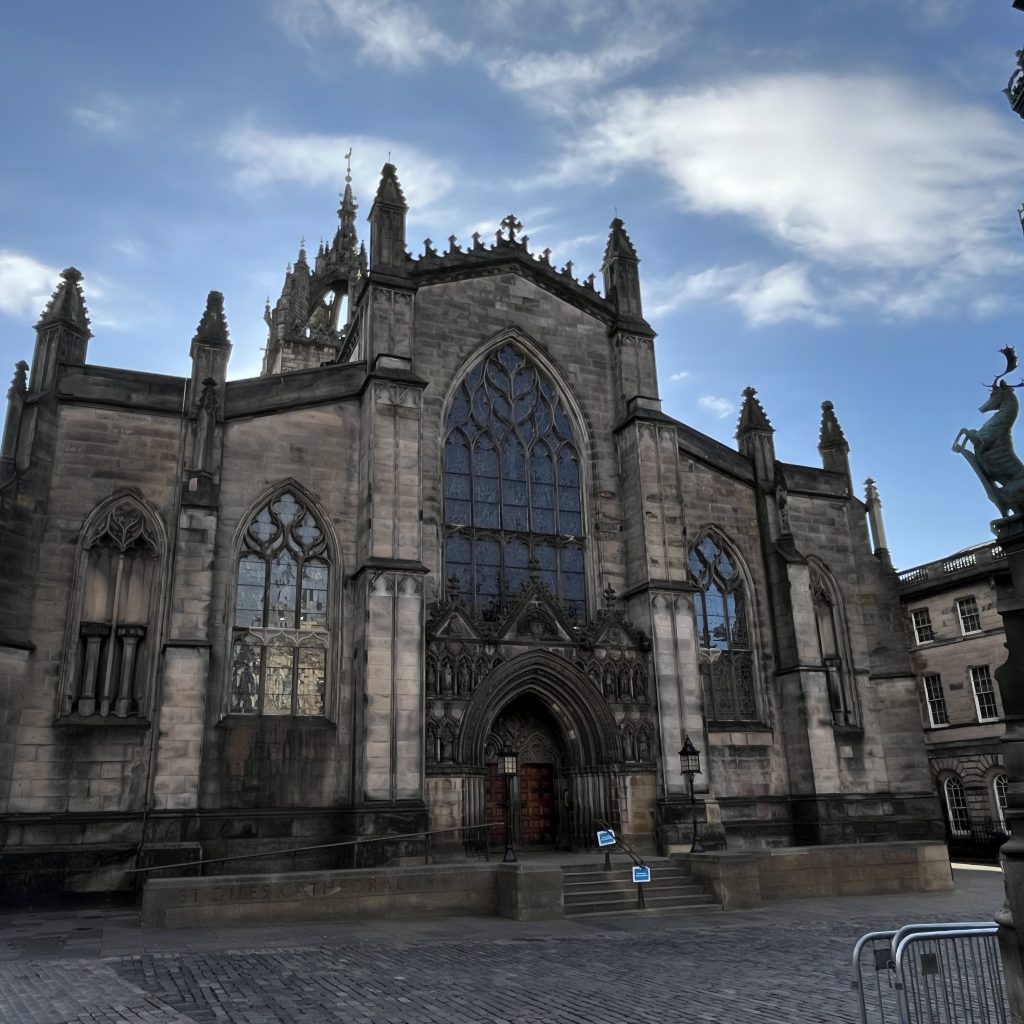 Eine alte, gotische Kirche von außen. Man sieht den blauen Himmel mit einigen Wolken. Darunter ein mächtiges Kirchengebäude.
